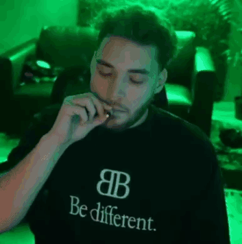 A Man Is Smoking A Cigarette While Wearing A Black Shirt That Says `` Be Different '' . GIF