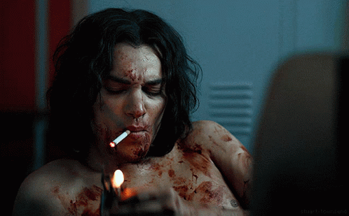 A Man Is Smoking A Cigarette With Blood On His Face GIF