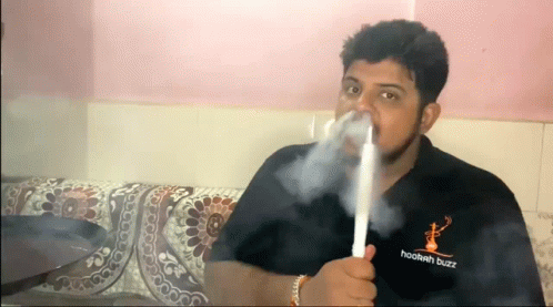 A Man Is Smoking A Hookah While Wearing A Hookah Buzz Shirt . GIF