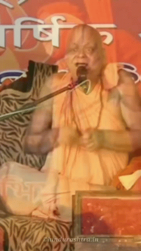 A Man Is Speaking Into A Microphone And The Website Behind Him Says ' Ohindurashtra.in ' GIF