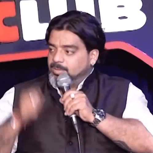 A Man Is Speaking Into A Microphone In Front Of A Club Logo GIF