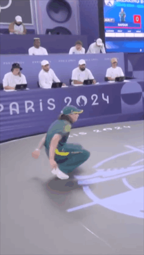 A Man Is Squatting Down In Front Of A Paris Sign GIF