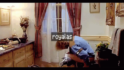 A Man Is Squatting On A Toilet In A Bathroom With A Sign That Says Royalas On It GIF