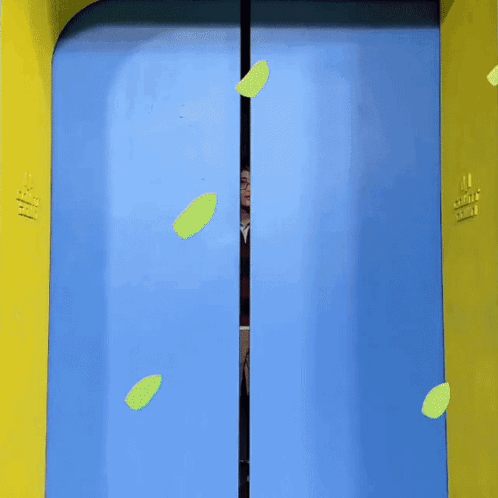 A Man Is Standing In A Blue And Yellow Doorway With A Heart On It GIF