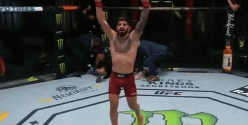 A Man Is Standing In A Boxing Ring With His Arms Up In The Air . GIF