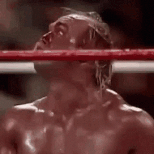 A Man Is Standing In A Boxing Ring With His Head Hanging Over The Ring . GIF