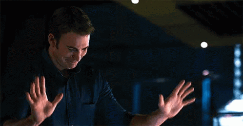 a man is standing in a dark room with his hands outstretched and smiling .