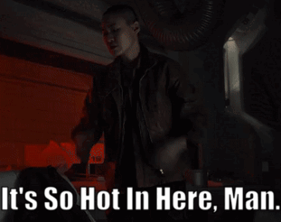 A Man Is Standing In A Dark Room With The Words " It 'S So Hot In Here Man " Above Him GIF