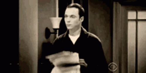 A Man Is Standing In A Doorway Holding A Stack Of Papers In His Hand . GIF