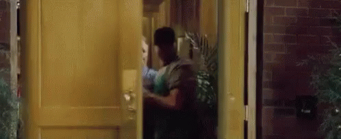 A Man Is Standing In A Doorway Holding A Woman 'S Hand . GIF
