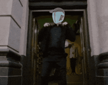 A Man Is Standing In A Doorway With A Mask On His Head GIF