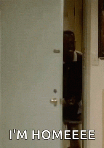 A Man Is Standing In A Doorway With The Words `` I 'M Homeeee '' Written On The Door . GIF