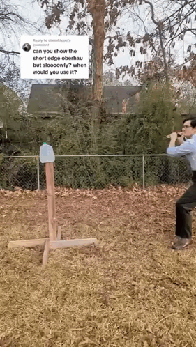 A Man Is Standing In A Field Holding A Hammer And A Bottle Of Water . GIF