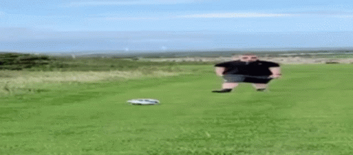 a man is standing in a field with a remote control car .
