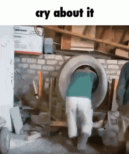A Man Is Standing In A Garage With A Tire In His Back And The Words Cry About It Above Him GIF