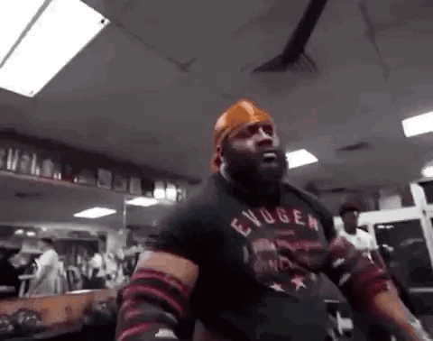 A Man Is Standing In A Gym Wearing A Bandana And A Black Shirt . GIF