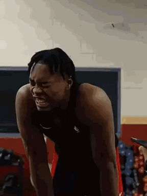 a man is standing in a gym with his arms outstretched and his mouth open .