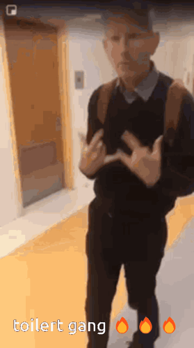 A Man Is Standing In A Hallway With The Words Toilet Gang On The Bottom Right GIF