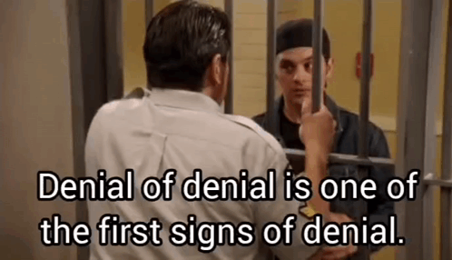 A Man Is Standing In A Jail Cell With A Prisoner Behind Bars . GIF