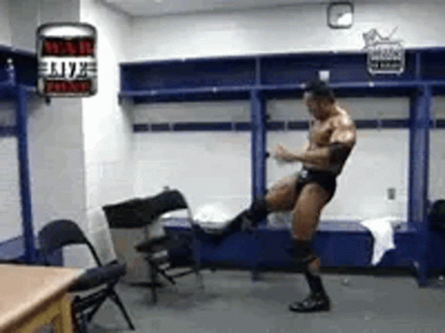 A Man Is Standing In A Locker Room Kicking A Chair In The Air . GIF