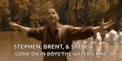 A Man Is Standing In A River With His Arms Outstretched . GIF
