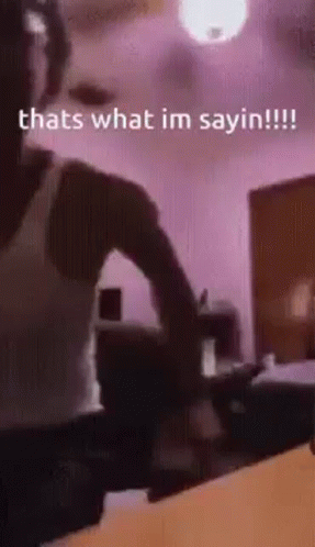 A Man Is Standing In A Room With A Ceiling Fan And A Purple Wall . GIF