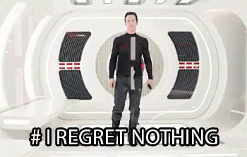 A Man Is Standing In A Room With The Words # I Regret Nothing On The Bottom . GIF