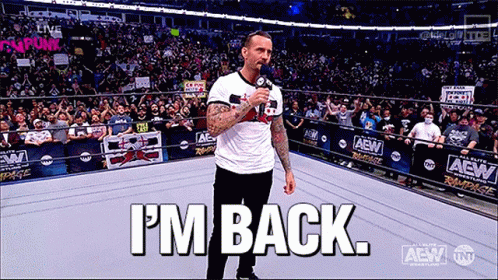 A Man Is Standing In A Wrestling Ring Holding A Microphone And Says I 'M Back GIF