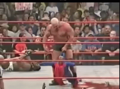 A Man Is Standing In A Wrestling Ring With A Crowd Watching . GIF