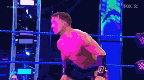 A Man Is Standing In A Wrestling Ring With A Fox Logo Behind Him GIF