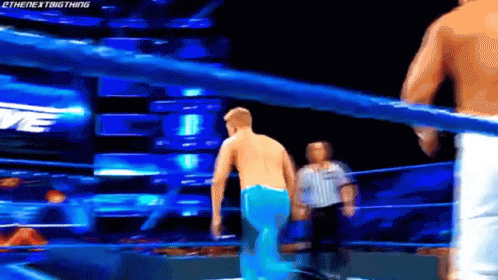 A Man Is Standing In A Wrestling Ring With A Referee Watching . GIF