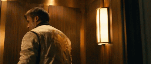 A Man Is Standing In An Elevator With A Light On The Wall GIF