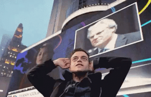 A Man Is Standing In Front Of A Billboard With His Hands On His Head . GIF