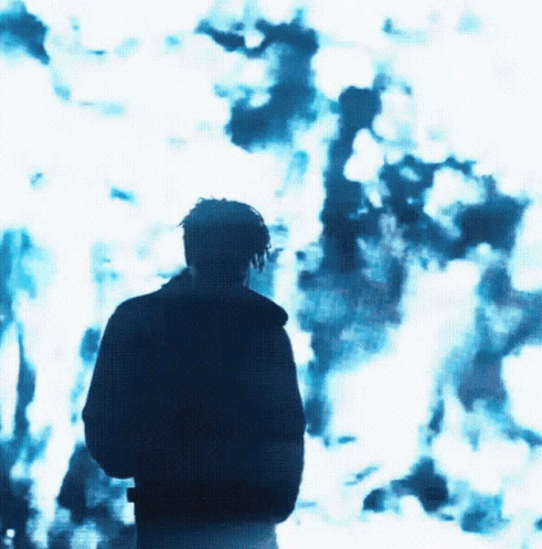 A Man Is Standing In Front Of A Blue Background GIF