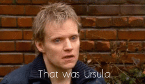 a man is standing in front of a brick wall and says that was ursula .