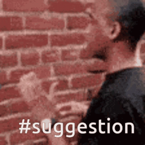a man is standing in front of a brick wall with the words #suggestion written on it
