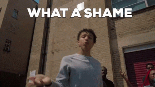 A Man Is Standing In Front Of A Brick Wall With The Words What A Shame Written Above Him GIF