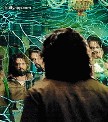 A Man Is Standing In Front Of A Broken Mirror With A Group Of People Behind Him . GIF