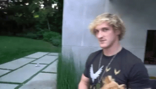 A Man Is Standing In Front Of A Building Wearing A Black T-Shirt With A Dog On It . GIF