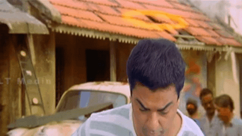 A Man Is Standing In Front Of A Building With The Word Medin On It GIF
