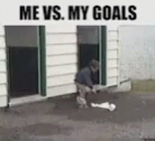 A Man Is Standing In Front Of A Building With The Words Me Vs. My Goals Above Him . GIF