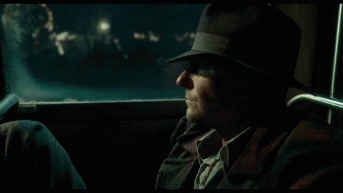 A Man Is Standing In Front Of A Cafe At Night GIF