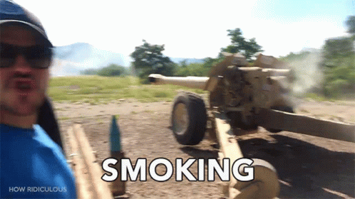 A Man Is Standing In Front Of A Cannon That Says Smoking On It GIF