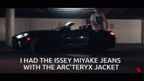 A Man Is Standing In Front Of A Car With The Words I Had The Issey Miyake Jeans With The Arc Teryx Jacket Below Him GIF