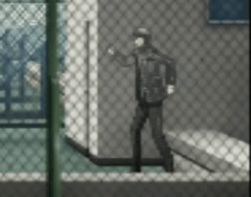 A Man Is Standing In Front Of A Chain Link Fence In A Room . GIF