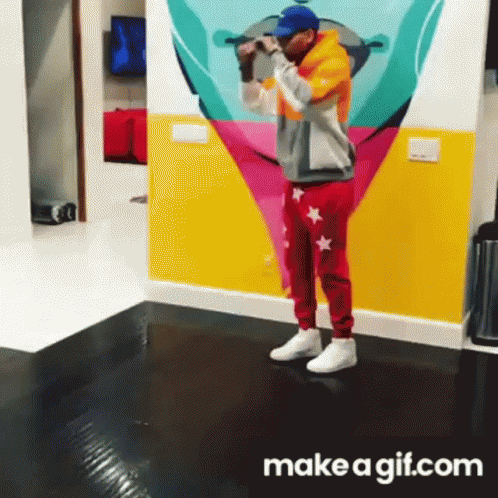 A Man Is Standing In Front Of A Colorful Wall With A Make A Gif.com Logo GIF
