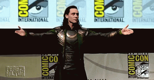 A Man Is Standing In Front Of A Comic Con Banner GIF