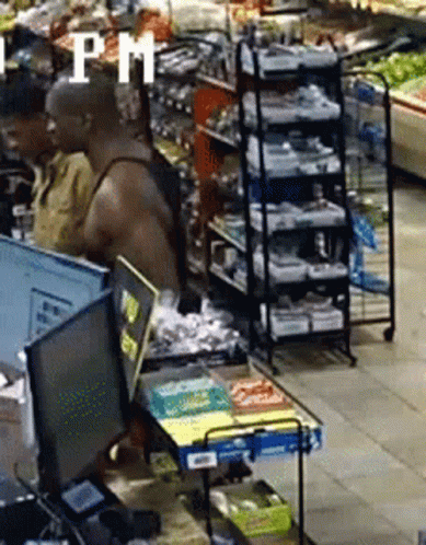 A Man Is Standing In Front Of A Computer In A Grocery Store With The Word Pm In The Corner . GIF