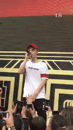 A Man Is Standing In Front Of A Crowd Holding A Microphone GIF