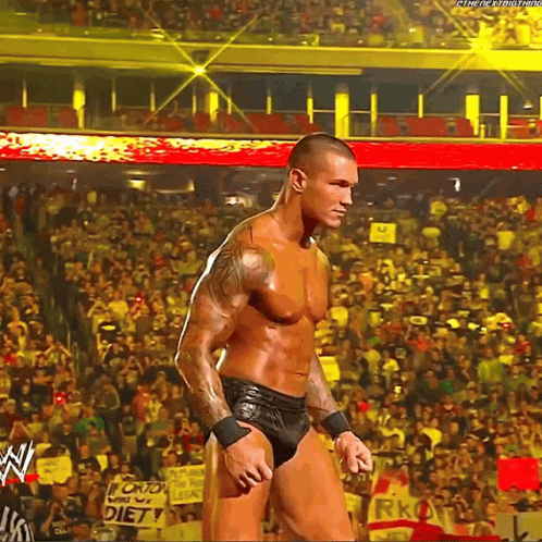 A Man Is Standing In Front Of A Crowd In A Stadium With A Sign That Says Diet On It . GIF